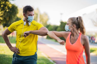 Young couple is getting ready for outdoor workout with protective masks. Covid-19 responsible behavior. clipart