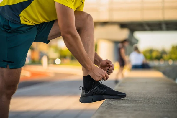 若い男はジョギングの前に靴ひもを結んでいる — ストック写真