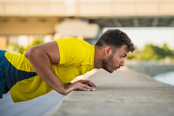 若い男が屋外で運動している 彼は押し上げをしている — ストック写真