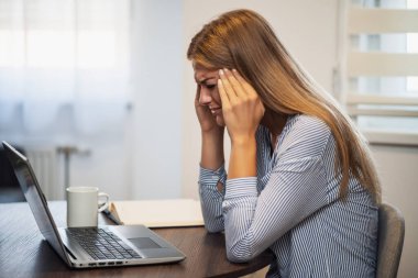 Genç modern kadın evden çalışıyor. Başı ağrıyor..