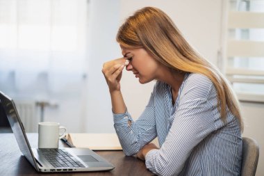 Genç modern kadın evden çalışıyor. Gözlerinde acı var..