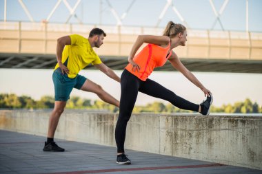 Genç çift dışarıda egzersiz yapıyor. Koşu için ısınıyorlar ve ısınıyorlar..