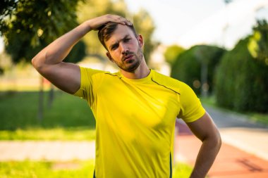 Genç adam dışarıda egzersiz yapıyor. Vücudunu esnetiyor ve koşuya hazırlanıyor..