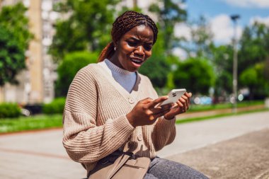 Afrikalı Amerikalı kadın internet mesajlaşması için akıllı telefon kullanırken endişeli.