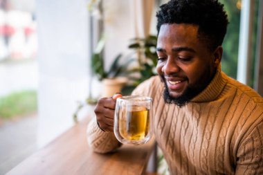 Barda oturmuş çay içen genç siyahi adamın portresini yakından çek..