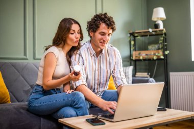 Yetişkin çift oturma odasında yatakta oturuyor ve bilgisayarlarını kullanarak online doktor randevusu alıyorlar..