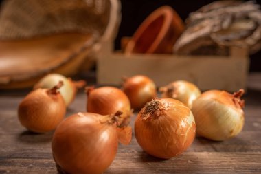 Arkadaki asma sepetleri ile eski bir ahşap masa içinde soğan