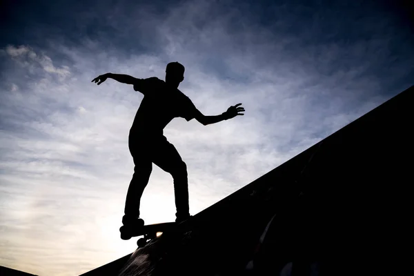 在一个溜冰公园里 在一个戏剧性的朦胧的天空中 一个溜冰者乘坐半管溜冰的剪影 — 图库照片