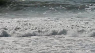Okyanus dalgalarının kıyıya yakın yuvarlanıp kırıldığı beyaz deniz köpüğü ve yüzey dokusunun sürekli hareket halinde olduğu bir video..