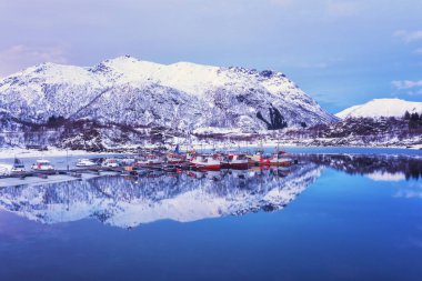 Sahne kış manzara Norveç'te. Balıkçı tekneleri dağ ridge arka planda göl günbatımı ışık yansıması ile Laupstad, Lofoten Adaları