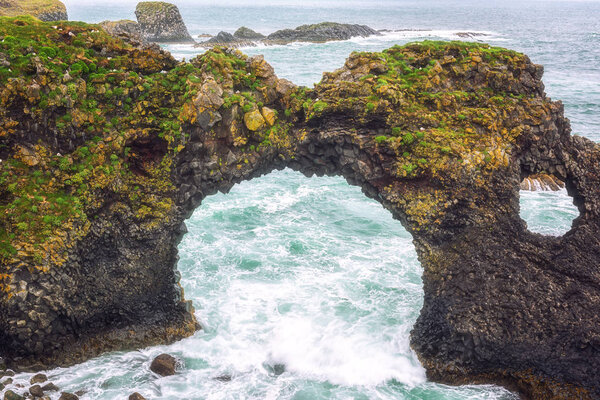 Amazing seascape, Gatklettur basalt rock arch at the volcanic cliff, Atlantic coast of Arnarstapi in the west of Iceland, natural travel background. Arnarstapi, Snaefellsnes peninsula, Iceland, Europe