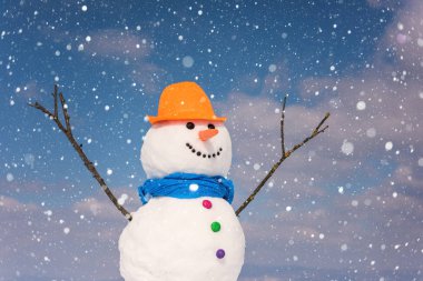 Kardan adam mavi gökyüzü arka plan düşen kar taneleri, mutlu kış konsepti ile gülümseyen şirin