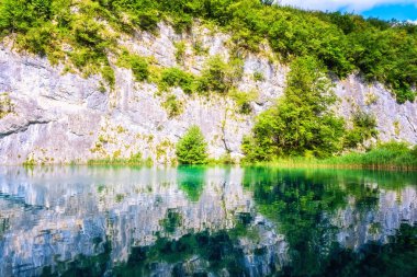 Plitvice Gölleri Milli Parkı, cliff derin zümrüt su, güneşli yaz arka plan yansıması ile