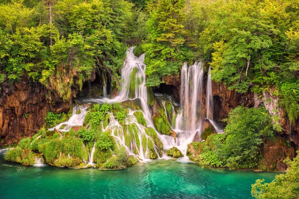 Waterfall in the green summer forest with turquoise water of the lake at Plitvice National park, Croatia. Nature background suitable for wallpaper, cover or guide book