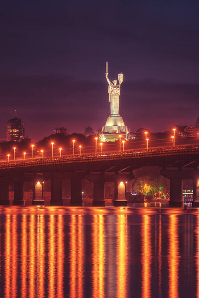 Kiev, Ukraine - May 04, 2018: View of the Paton bridge, Motherland monument and Dnieper river at night, beautiful cityscape with city lights, Kyiv the capital of Ukraine. Vertical image