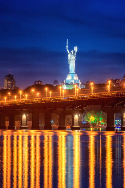 Kiev, Ukraine - May 04, 2018: View of the Paton bridge, Motherland monument and Dnieper river at night, beautiful cityscape with city lights, Kyiv the capital of Ukraine. Vertical image