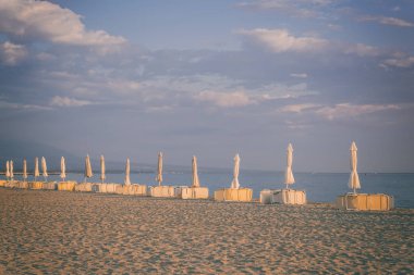 Sandy beach güzel mavi bulutlu gökyüzü ve plaj aksesuarları gündoğumu, deniz resort Platamonas yumuşak sabah ışık, Yunanistan ile
