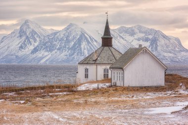 Güzel kış günbatımı manzarası, karlı rocky Dağları arka planda, Lofoten Adaları, Norveç sahil üzerinde yalnız kilise
