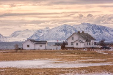 Karlı rocky Dağları arka planda, Lofoten Adaları, Norveç sahil güzel Norveç kış günbatımı manzara, beyaz ev
