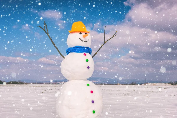 Kardan adam mavi gökyüzü arka plan düşen kar taneleri, mutlu kış konsepti ile gülümseyen şirin