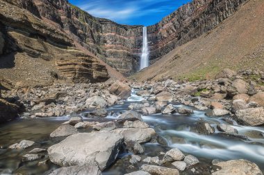 Şaşırtıcı doğa doğal görünümü muhteşem gorge, renkli kaya ve engebeli nehir düşen İzlanda'daki Hengifoss şelale. İzlanda yaz manzara mavi gökyüzü, açık ile arka plan seyahat