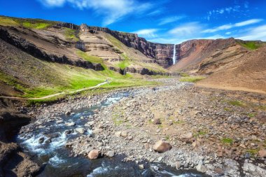 Şaşırtıcı doğa doğal görünümü muhteşem gorge, renkli kaya ve engebeli nehir düşen İzlanda'daki Hengifoss şelale. İzlanda yaz manzara mavi gökyüzü, açık ile arka plan seyahat