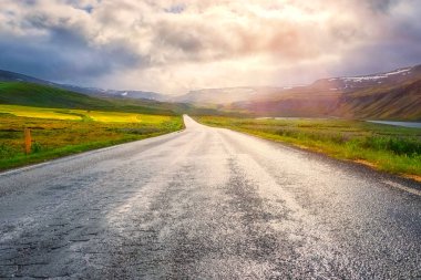 Şaşırtıcı doğa, doğa manzaralı boş asfalt yol ve bulutlu gökyüzü güneşli manzara. Hringvegur, İzlanda, ana çevre yolu açık yaz arka plan seyahat