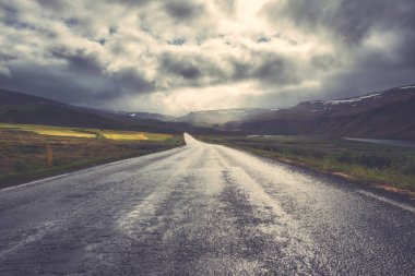 Şaşırtıcı doğa, vintage peyzaj manzaralı boş asfalt yol ve bulutlu gökyüzü ile. Hringvegur, İzlanda, ana çevre yolu açık yaz arka plan seyahat