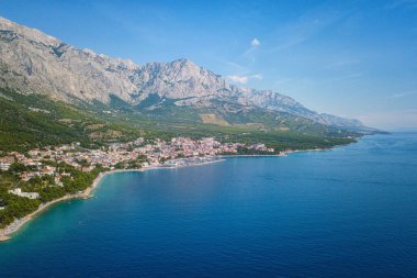 Hırvatistan, Dalmaçya 'daki Makarska Riviera' nın muhteşem hava manzarası. Adriyatik deniz kıyısındaki popüler turizm beldelerinin gündüz manzarası kayalık Dinara dağlarının eteklerinde, dış seyahat arka planında