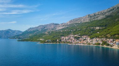Hırvatistan, Dalmaçya 'daki Makarska Riviera' nın muhteşem hava manzarası. Adriyatik deniz kıyısındaki popüler turizm beldelerinin gündüz manzarası kayalık Dinara dağlarının eteklerinde, dış seyahat arka planında