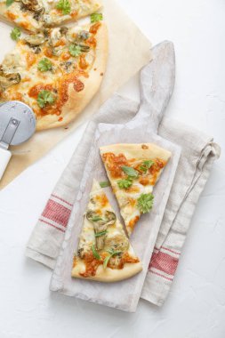 İki dilim pizza ile enginar beyaz kesme tahtası üzerinde