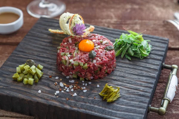 Tártaro de carne com alcaparras, pepino em conserva e cebolas frescas no fundo escuro — Fotografia de Stock