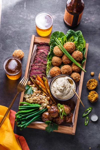 Middle eastern or arabic dishes and assorted meze on a dark background. Meat, falafel, baba ghanoush, vegetables. Halal food. Space for text. Top view.