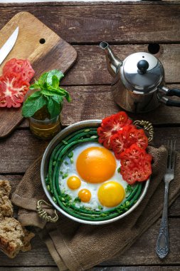 Domates ve yeşil fasulye, kopya alanı ile bakır tavada yumurta güneşli tarafı kızarmış.