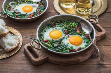 Yeşil shakshuka. Kızarmış yumurta taze ıspanak, ramson, gri bir arka plan, üstten görünüm üzerinde bir tavada pırasa ile