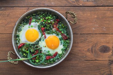 Yeşil shakshuka. Kızarmış yumurta taze ıspanak, ramson, gri bir arka plan, üstten görünüm üzerinde bir tavada pırasa ile