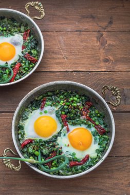 Yeşil shakshuka. Kızarmış yumurta taze ıspanak, ramson, gri bir arka plan, üstten görünüm üzerinde bir tavada pırasa ile
