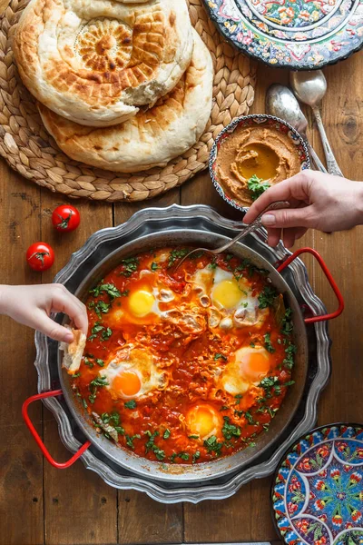 Aile kahvaltıyla shakshuka, ekmek ve humus. Rustik tarzı