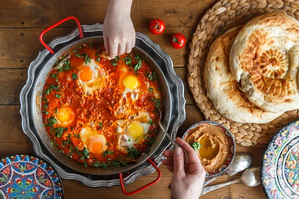 Aile kahvaltıyla shakshuka, ekmek ve humus. Rustik tarzı