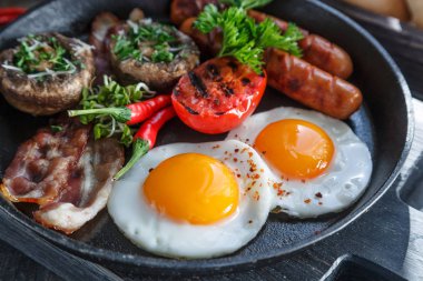 Bir tavada kızarmış yumurta, sosis, jambon, mantar, reçel ve portakal suyu ile İngiliz kahvaltısı görünümü karanlık taş zemin üzerine kapatın