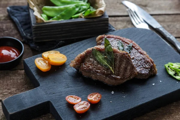 Friptură de carne Picanha, tradițională braziliană tăiată pe placa de tăiere neagră . — Fotografie, imagine de stoc