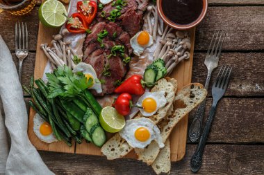 Kahvaltı yemek çeşitli düz yatıyordu. Et, yumurta, sebze, ekmek vb ile açık büfe ahşap tahta üzerinde üstten görünüm