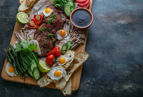 Breakfast board fullof eggs, meat, vegetables, bread, meat and tea, top view