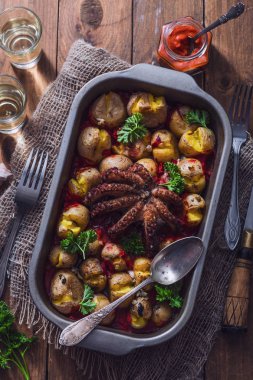 Grilled octopus with baked potatoes, tomato sauce and wine clipart