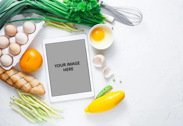 Cooking recipes on ipad with vegetables on background, copy space