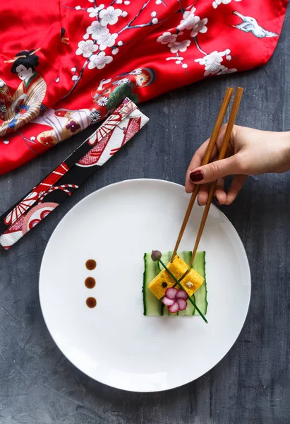 Χέρι με chopstiks παίρνει ένα κομμάτι του tamagoyaki — Φωτογραφία Αρχείου
