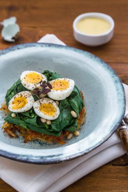 Bıldırcın yumurtası ıspanak ve rosti üzerinde ahşap arka plan, görünümü Kapat