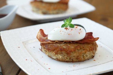 Patates rosti, haşlanmış yumurta ve pastırma üstte.