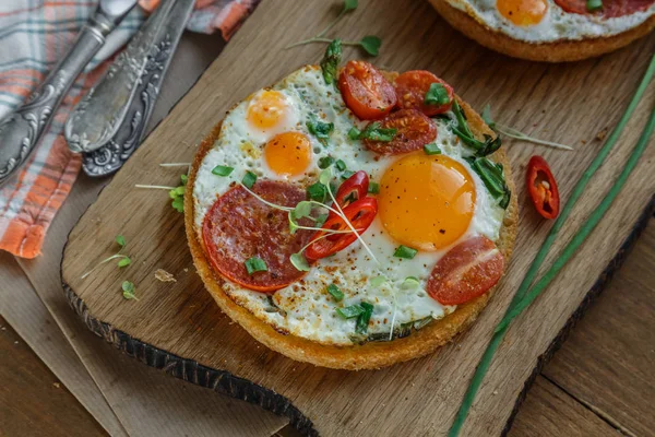 Huevos fritos lado soleado con tomate y pan en la tabla de cortar —  Fotos de Stock