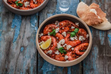 Bir masada bir tabak üzerinde beyaz peynir ile Karides saganaki